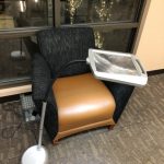 Lighted magnifier stand set up by a reading chair